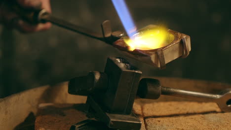 traditional goldsmith pouring molted metal in mold with goldsmith tools