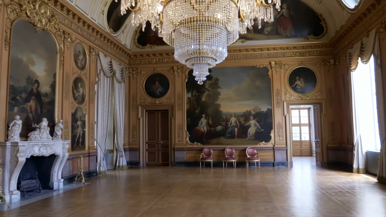 Sala da ballo vuota e ornata con lampadario di cristallo, modanature dorate, affreschi sul soffitto, drappeggi dal pavimento al soffitto