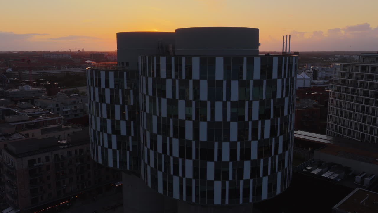 Aerial drone view of modern round CPH Towers building in Orestad, Copenhagen, Denmark at sunset