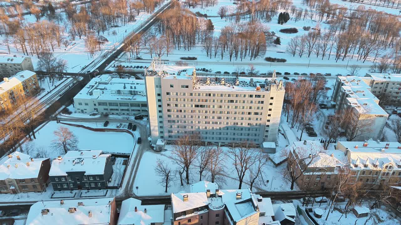 Заснеженный городской пейзаж Риги с жилыми домами, парком, колесом обозрения и Рижской телебашней при зимнем дневном свете