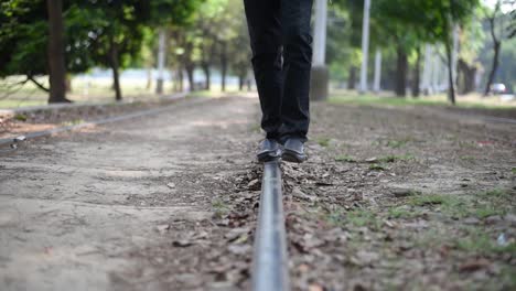 young happy male balances himself and walks on tram tracks on streets