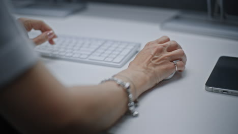 close up of female financial analyst or stock exchange trader using computer mouse, typing on keyboard, working on pc. successful businesswoman works in investment bank office or financial agency.