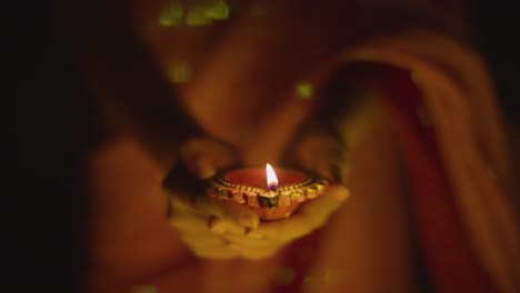 cerca de una mujer celebrando el festival de diwali sosteniendo una lámpara de aceite diya encendida 1