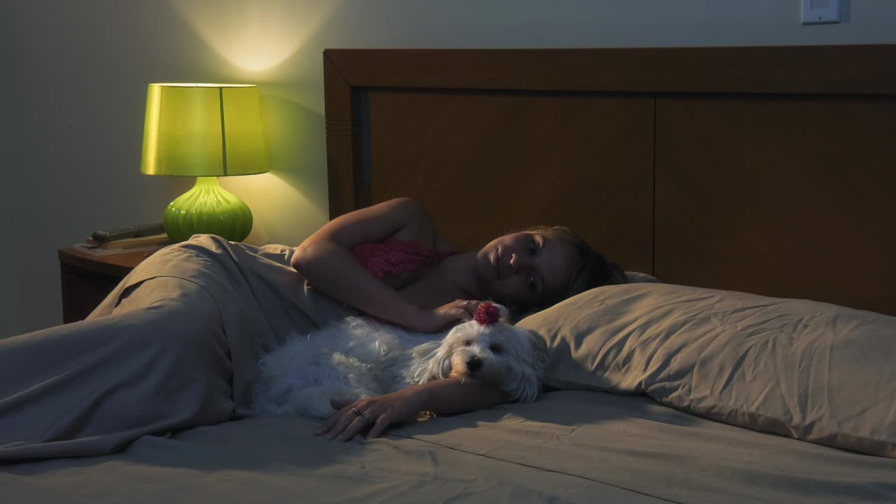 mujer acariciando al perro en la cama durmiendo por la noche