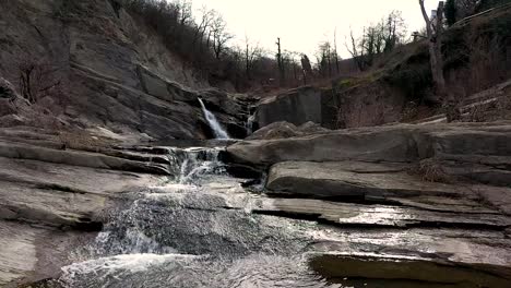 Close-near-drone-flight-over-water-in-near-of-a-waterfall-at-daytime