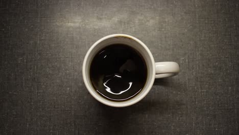 a top shot of a man's hand stirring coffee and pouring milk into the cup