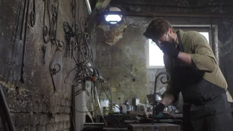 worker polishing metal billet in smithy