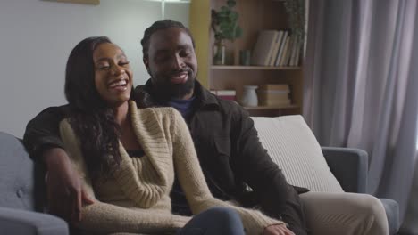 portrait of smiling young couple relaxing at home sitting on sofa