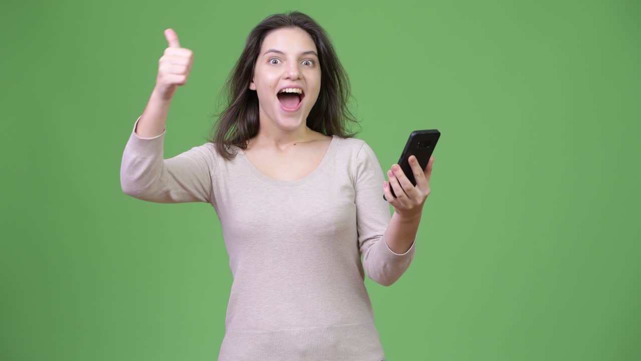 Young happy beautiful woman using phone and giving thumbs up