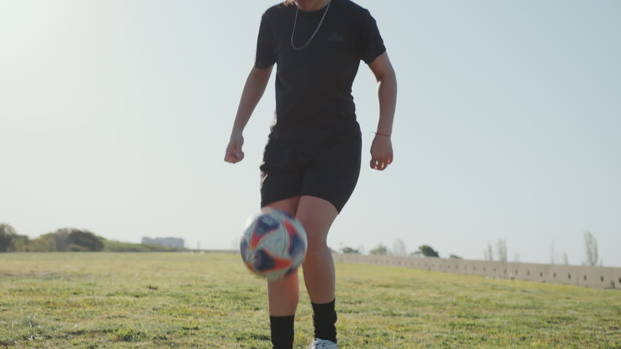 Female Athlete Doing Kick-Ups with Soccer Ball on Green Field