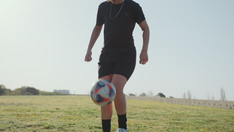 atleta femenina haciendo kick-ups con una pelota de fútbol en el campo verde