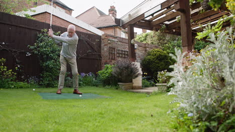 man practicing golf in his backyard