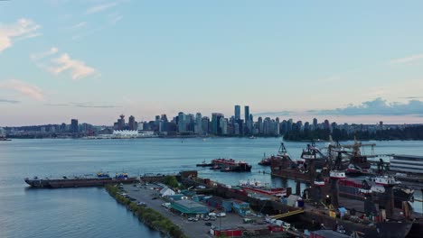 impresionante toma aérea de drones sobre contenedores de envío y barcos industriales en el norte con los rascacielos del paisaje urbano de vancouver en el fondo