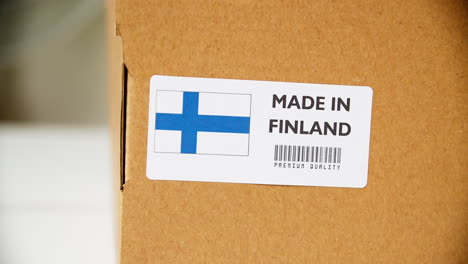 hands applying made in finland flag label on a shipping cardboard box with products