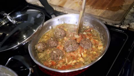 aerial shot of meatballs cooking in a steel pan preparing ingredients to make vegan beyond meatballs with spaghetti and meat sauce