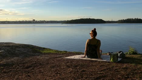 picnic al atardecer mujer mirando el mar tranquilo en la orilla rocosa, levantando grúa disparado