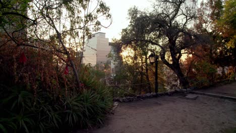 Truck-right-of-trail-in-Santa-Lucia-Hill-surrounded-by-autumnal-trees-and-vegetation-at-gondel-hour,-Santiago,-Chile