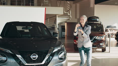 mujer mirando con entusiasmo un coche nuevo en una sala de exposiciones