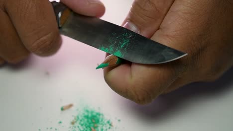 Footage-of-hands-slowly-sharpening-a-pencil-and-some-coloured-pencils-with-a-sharp-knife