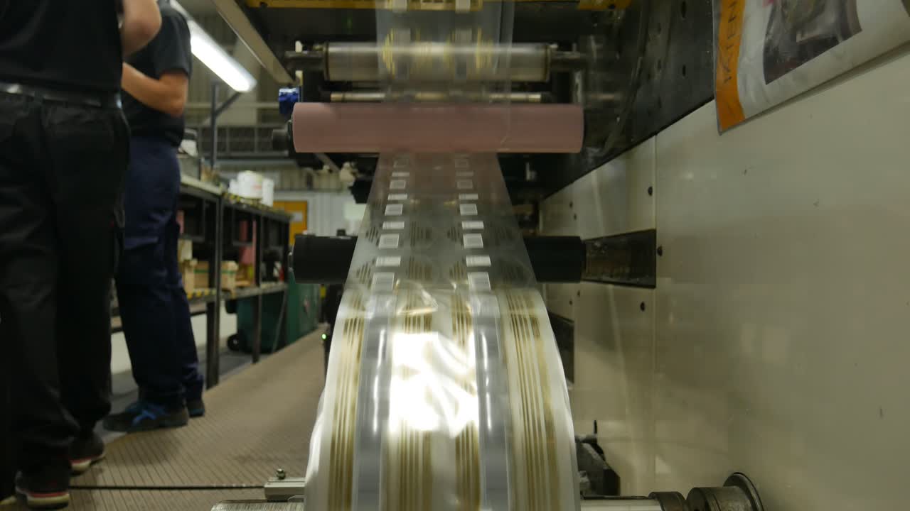 labeling machine in chain production for large-scale manufacturing, gold labels circulate at high speed in front of the camera