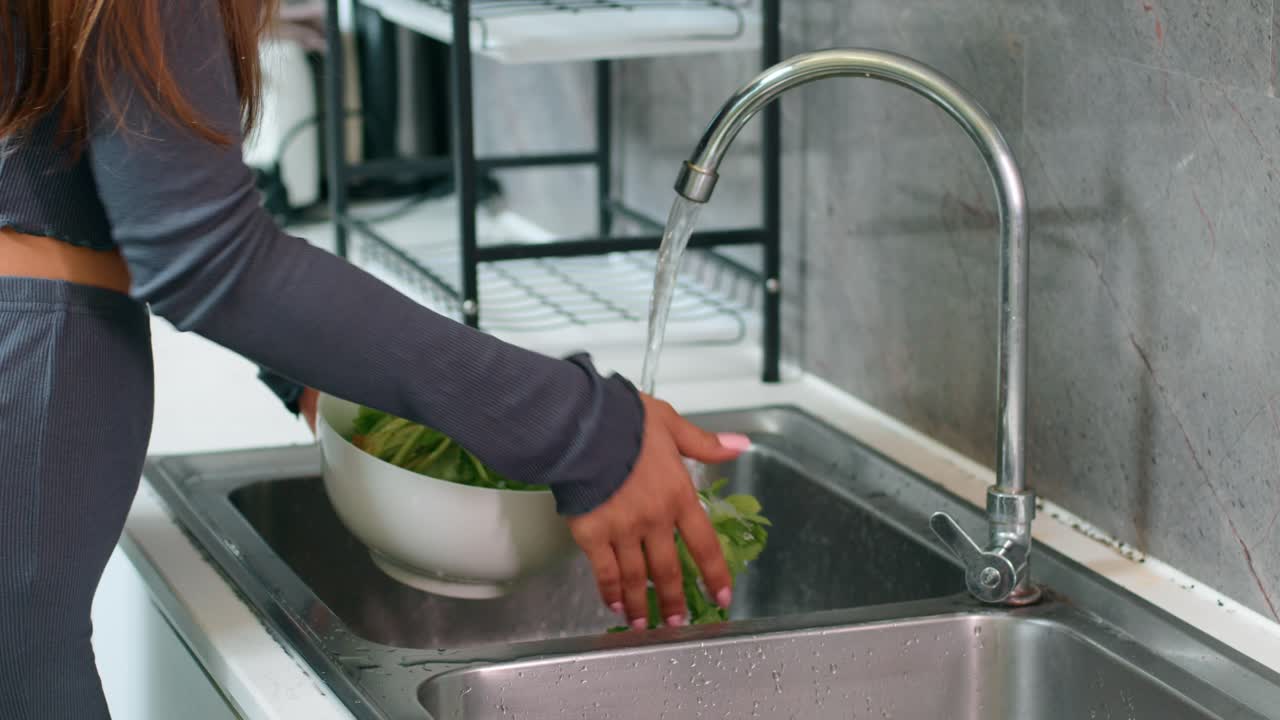 Mujer lavando apio en un fregadero de cocina