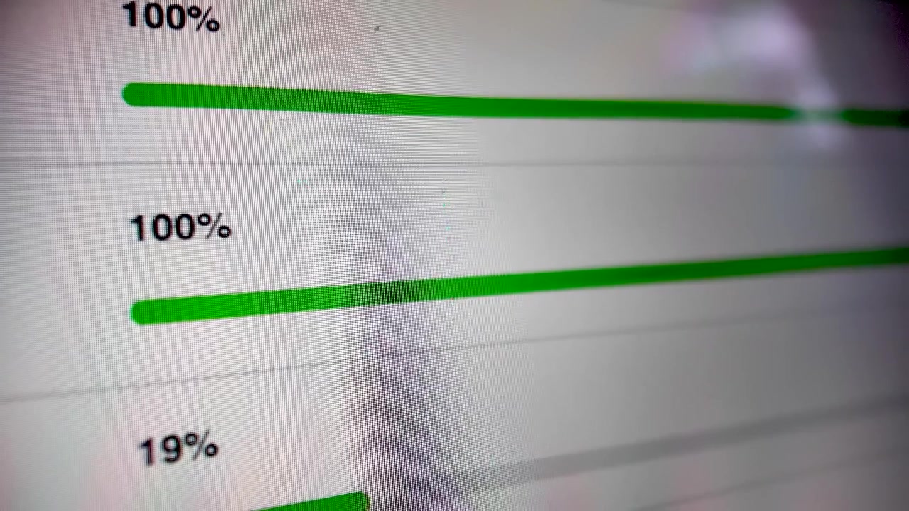 A close-up view of a green progress bar on a digital screen, indicating data loading with increasing percentages.