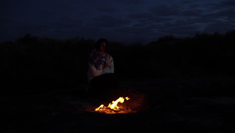 young girl alone in dark woods alone by campfire