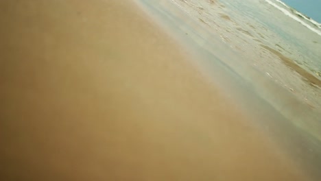vertical shot:-vertical aerial view of waves break on white sand beach. sea waves on the beautiful beach aerial view drone 4k shot.close-up shot of calming foamy water.