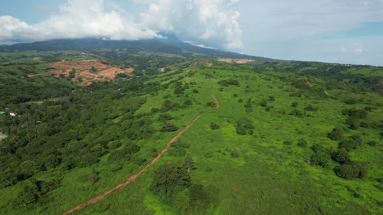 Level aerial showing lush greenery with a small trail winding through the hills, captured near the town port and coastal landscape of Mariveles, Bataan
