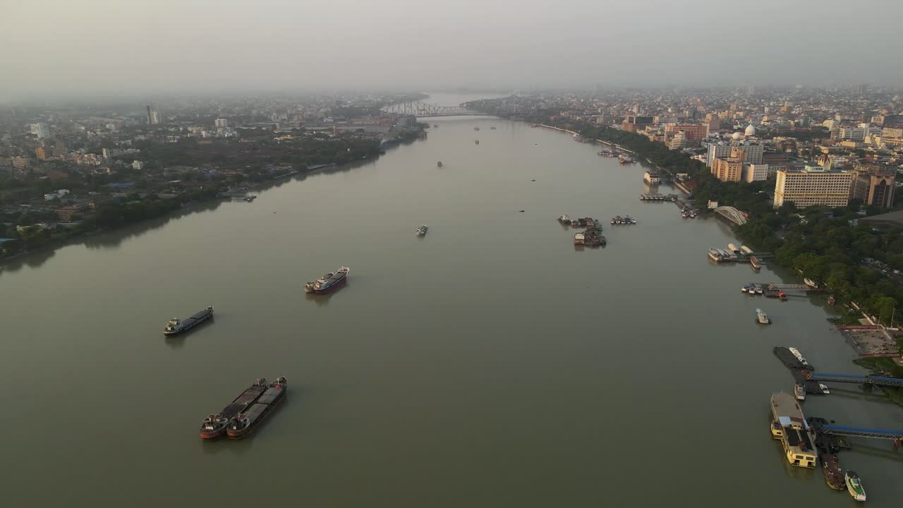 Aerial drone shot of Howrah Bridge spanning the Hooghly River, a landmark of Kolkata's rich heritage.