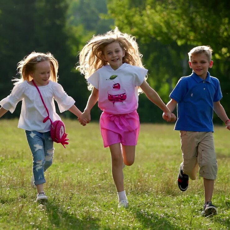 Bambini felici corrono insieme nel parco tenendosi per mano. I bambini camminano all'aperto. Quattro bambini corrono gioiosamente. Bambini piccoli che si divertono in estate.