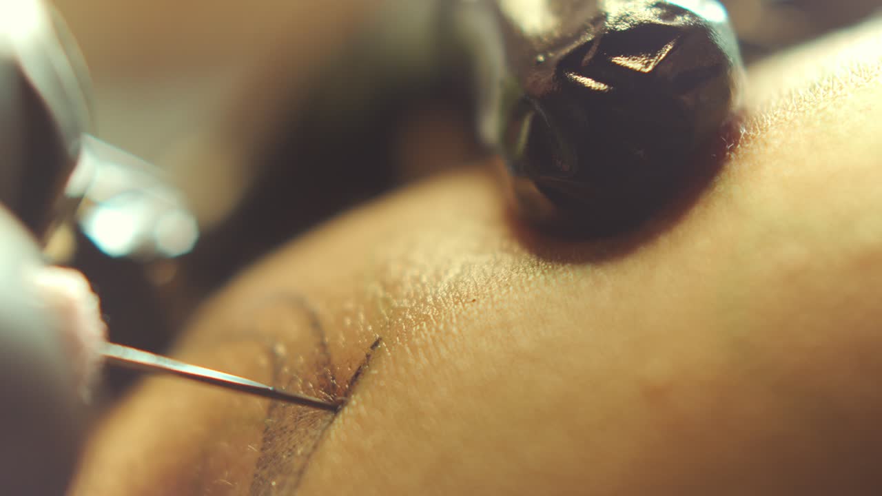 Hands of Tattoo Artist Using Needle to Insert Ink into Skin