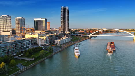 a barge and riverboat on the danube near the appolo bridge. view on the waterfront of bratislava, slovakia with modern architecture