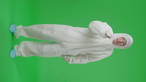full body of angry asian man wearing personal protective equipment uniform ppe and pointing displeased and frustrated to the camera in the green screen studio