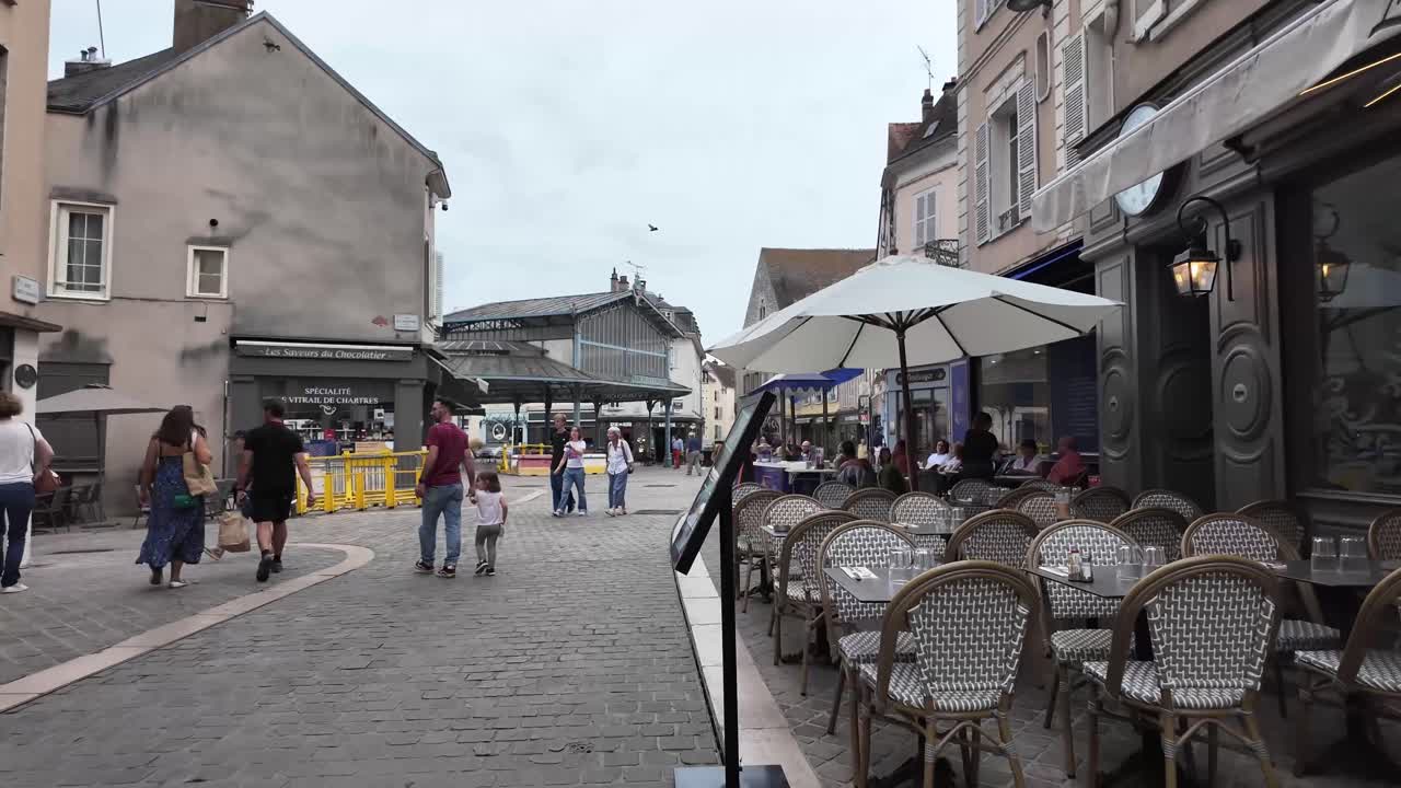 Restaurants, coffee shops and cobbled street with people walking in the old town Chartres, France