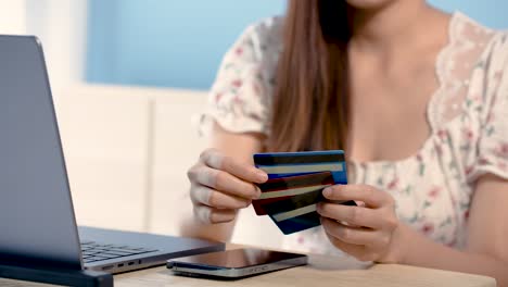 4k 50fps, asian woman hand close-up credit card holder three in hand, sitting in front of a laptop computer, choosing a credit card. to prepare online shopping, sitting in bed, online shopping concept