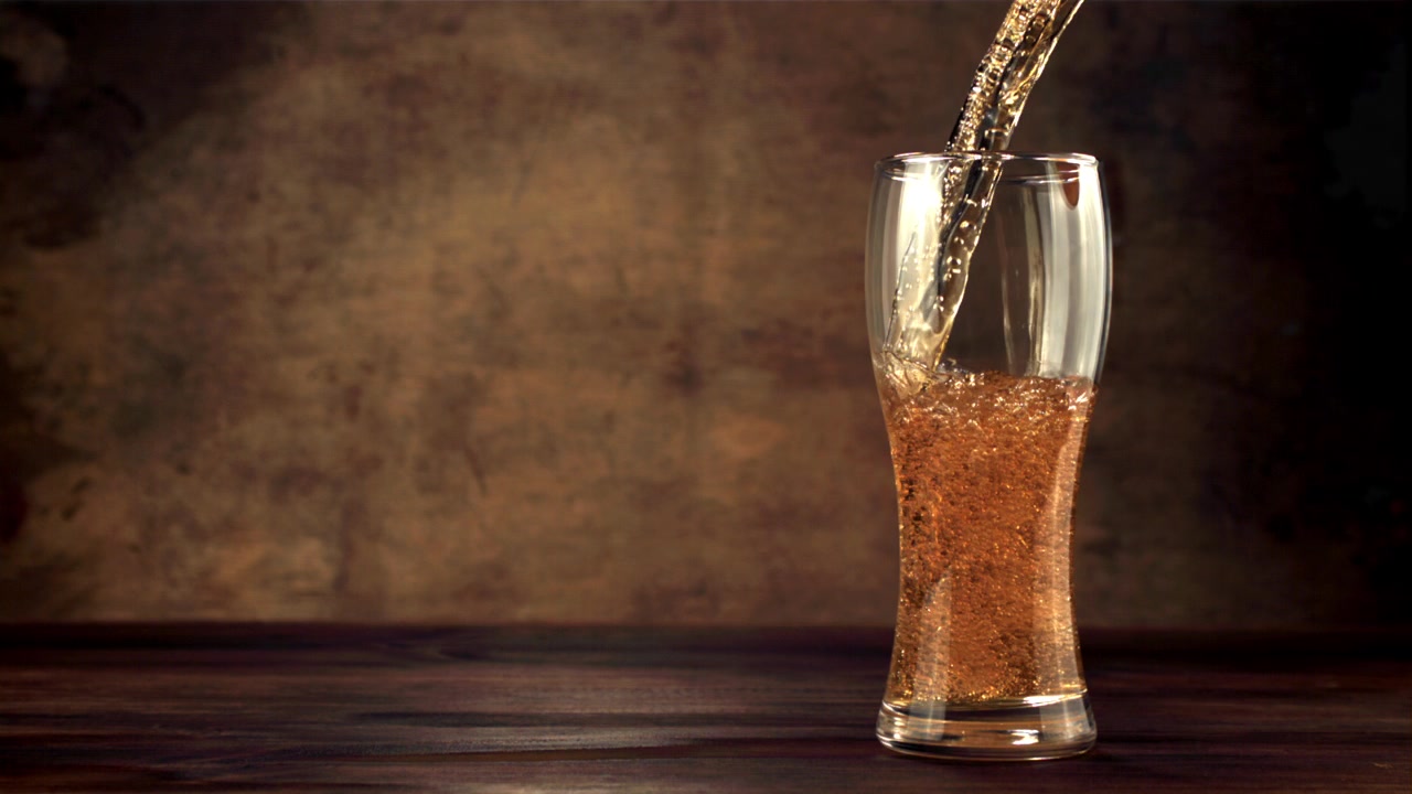 Birra dorata rinfrescante versata in un bicchiere su un tavolo rustico