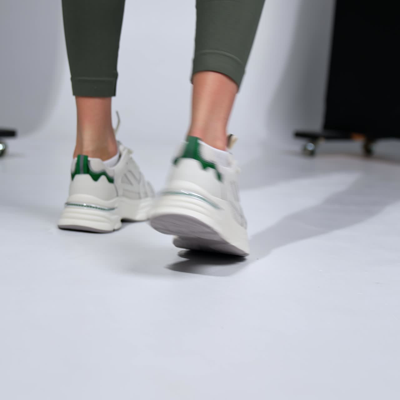 Fitness lady in leggings and comfortable sneakers. Stylish sport footwear close up in studio. Blurred backdrop