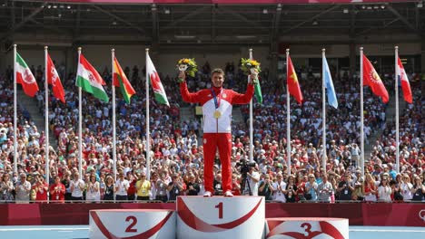 victorious athlete celebrates gold medal achievement on the podium surrounded by national flags and an enthusiastic crowd cheering in joyful support and pride