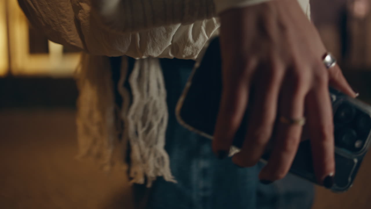 mujer con la mano sosteniendo un teléfono inteligente por la noche paseo por la ciudad primer plano. mujer desconocida teléfono