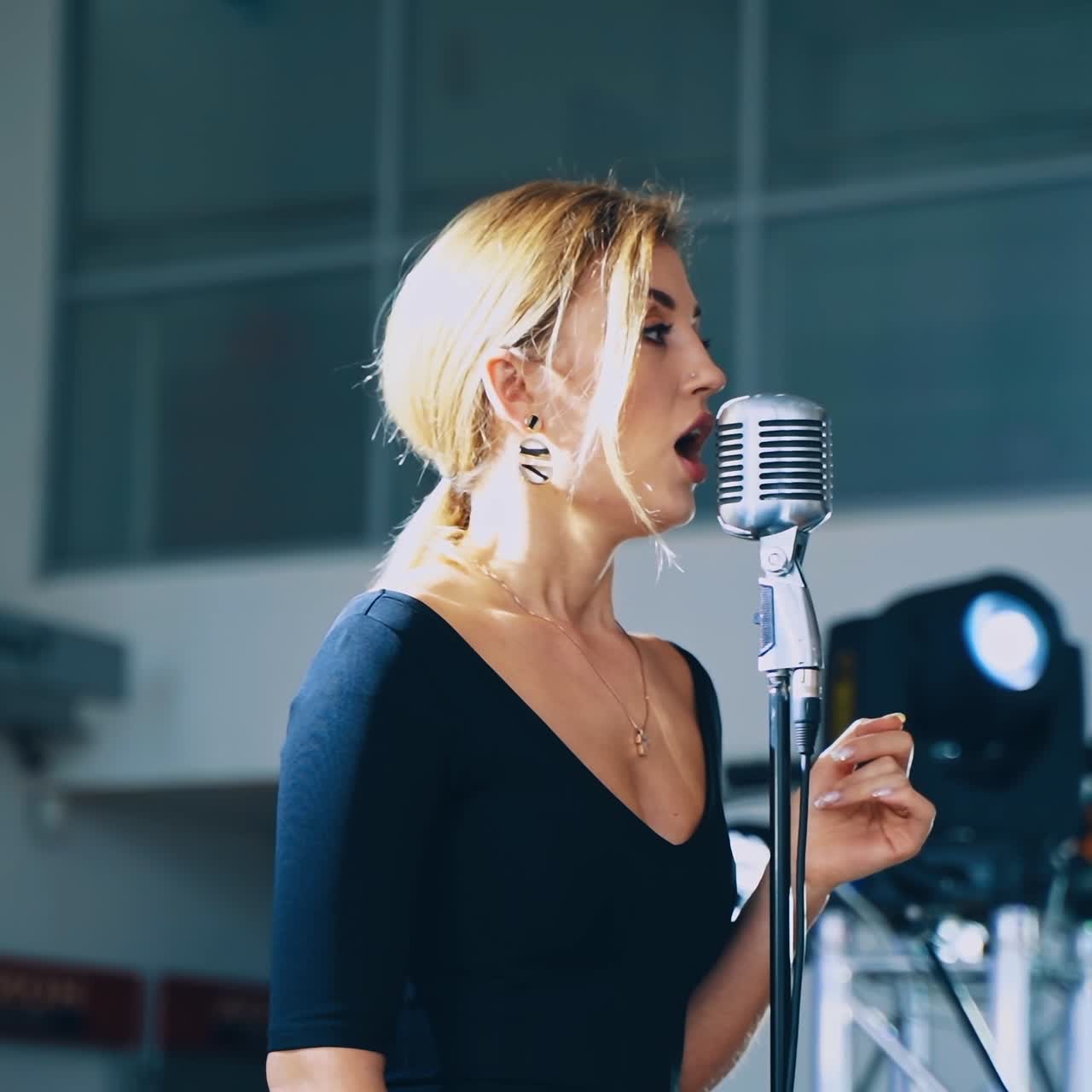 Musical star on the stage. Attractive woman singer performing a live music into the microphone for special event. Slow motion.