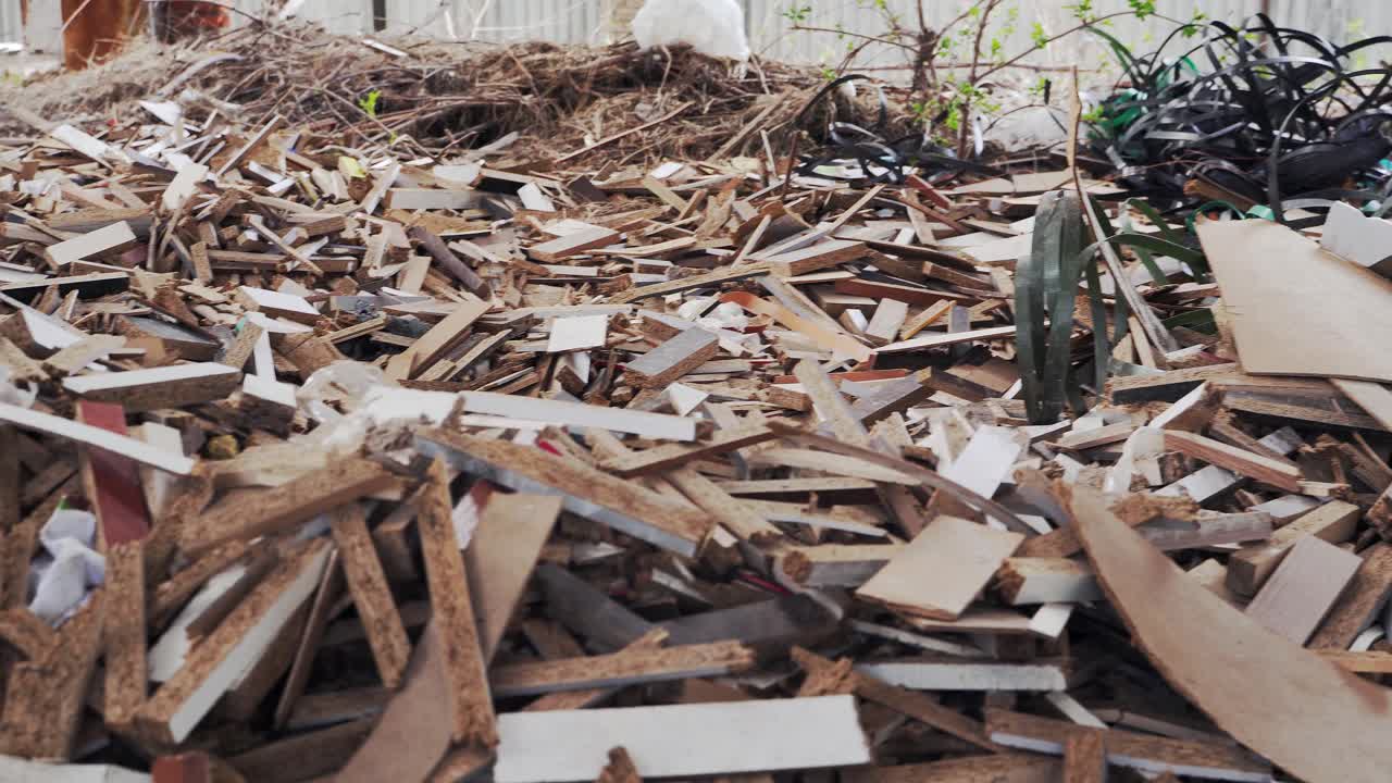 Production waste in the yard. Heaps of rubbish, chipboard fragments, plastic bands. Environmental pollution