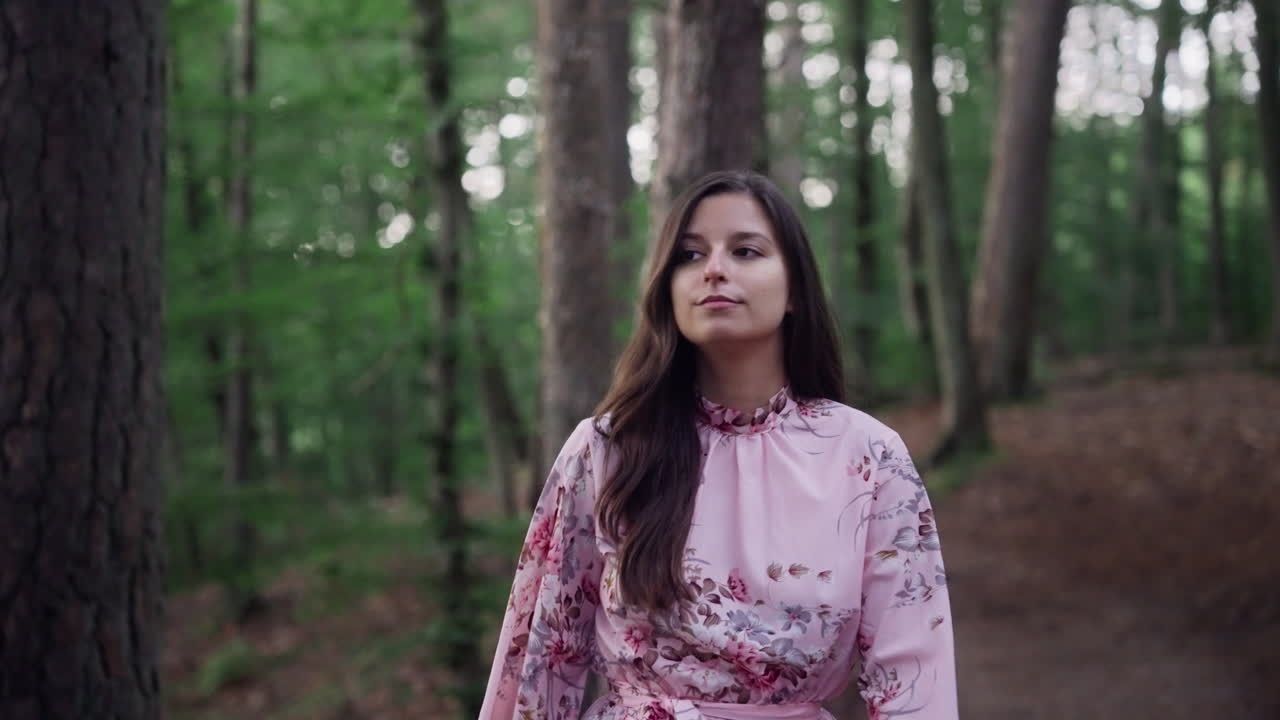 Linda garota vestindo um vestido rosa floral caminhando sozinha na natureza selvagem.