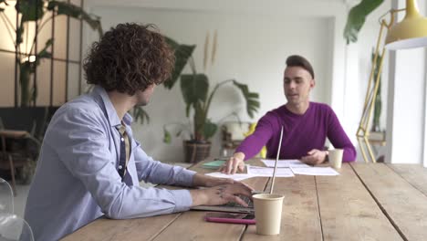 young gay couple reading good news in document, smiling excited by mail letter, checking paying domestic bills online on laptop, discussing budget planning