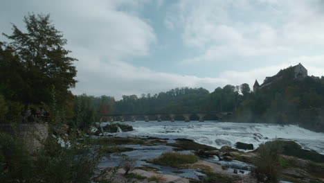 Famous-scenic-view-of-large-castle-above-cliffs-at-Rhine-Falls-in-Schaffhausen-Switzerland,-Europe