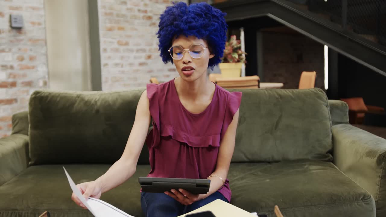 Happy biracial businesswoman with blue afro and having video call and using tablet, slow motion