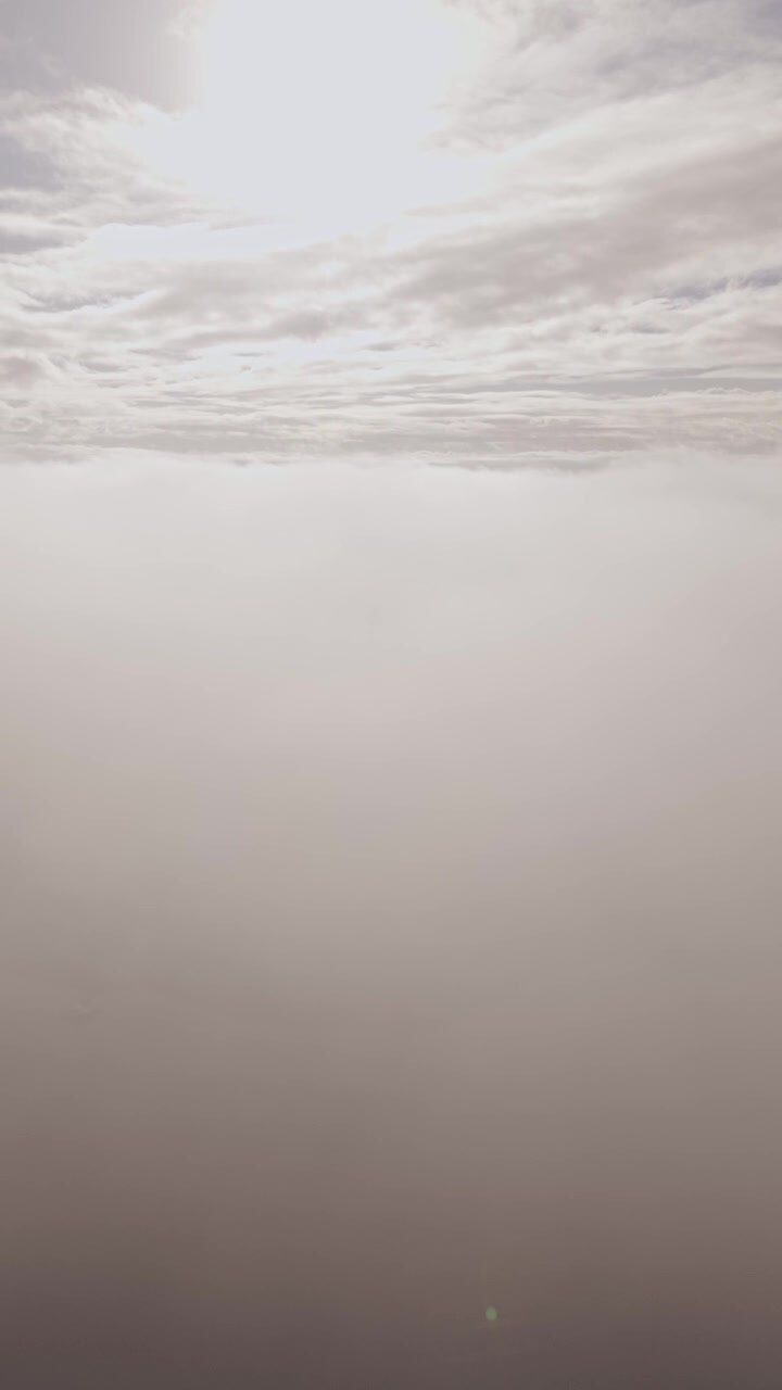 Vertical drone video captures an aerial perspective as sunlight breaks through thick, dramatic cloud cover.