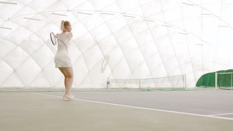 WIDE-SIDE-VIEW-Young-Caucasian-female-tennis-player-hitting-a-ball-during-game-or-practice.-100-FPS-slow-motion,-4K-UHD-RAW-graded-footage