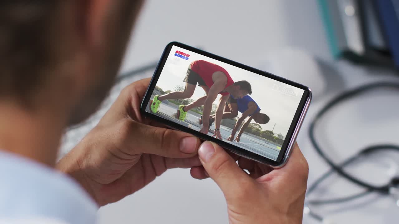 compuesto de un médico masculino viendo un evento de atletismo en un teléfono inteligente
