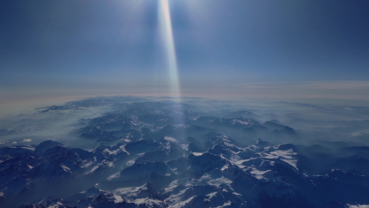 Una veduta aerea elevata dal lato sinistro della catena dei Pirenei, ripresa da 10.000 metri di altezza, con un raggio di sole che illumina la scena. Controluce.